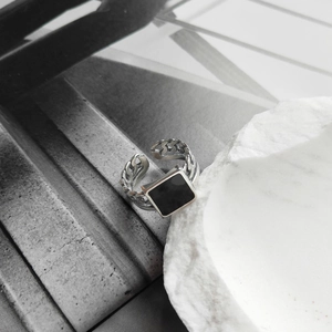 Detailed shot of S925 silver chain ring with black square resin inlay on white stone