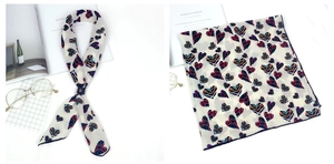 Détail d'un foulard artistique en soie avec des motifs de cœurs colorés sur satin beige