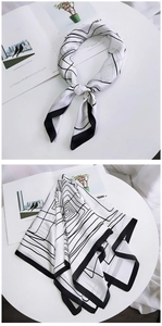 Macro shot showing smooth silk texture and black and white geometric lines on the scarf