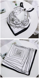 Detailed view of square silk scarf with minimalist black geometric lines and satin finish