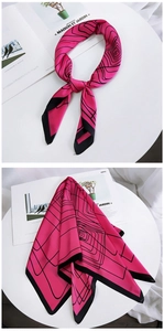 Close-up of fuchsia silk scarf with black geometric spiral lines and refined edges