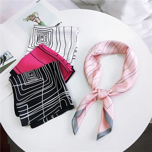 Elegant silk scarves set in geometric patterns and stripes on white marble surface