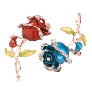 Detailed close-up of crystal rose brooches in red and blue enamel with gold finish