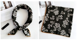 Detail view of dark green floral silk scarf with vintage pattern and orange borders