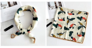 Detailed flat lay of a square silk scarf with colorful tropical birds and green leaves print