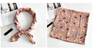 Detail of dusty pink silk-like scarf featuring colorful feather prints and fine edge stitching