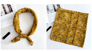 Close-up of ginger yellow square scarf with white daisy print and neatly hemmed edges