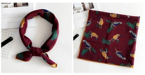 Detail of dark red square scarf featuring tropical bird and leaf patterns in a split view