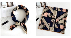 Detail view of square scarf with geometric blue, pink, and striped patterns in satin finish