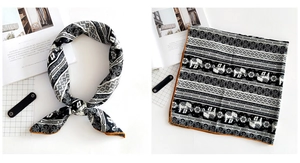 Detail of linen square scarf featuring elephant print and vibrant orange border