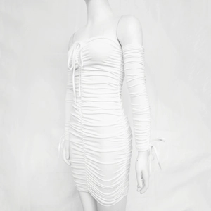 Détail de la robe mini plissée blanche et texture des manches longues froncées