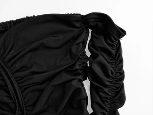 Détail du tissu plissé noir et du cordon de serrage réglable sur la robe à épaules dénudées