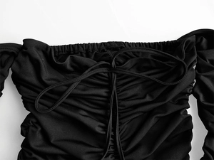 Détail d'une robe noire à épaules dénudées avec tissu plissé et cordon de serrage
