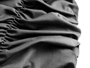 Détails macro de la texture du tissu noir plissé et des finitions de la robe