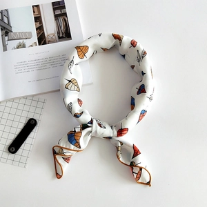 Linen square scarf with colorful leaf print and orange border tied in a stylish ring knot