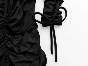 Gros plan sur la robe plissée noire avec détails de poignets à lacets ajustables