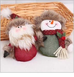 Close-up of Santa and Snowman plush ornaments with red burlap texture and berries