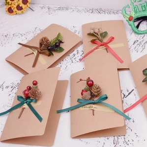 Christmas kraft greeting cards decorated with pine cones, red berries and festive ribbons