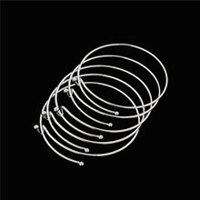 Set of six silver stackable open wire bracelets with sphere ends on black background