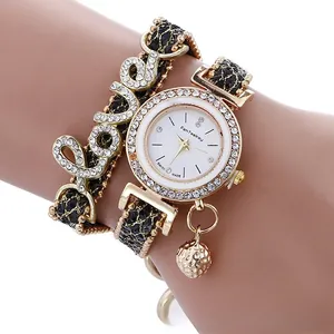 Detail of gold LOVE charm watch featuring crystal bezel and braided leather bracelet strap