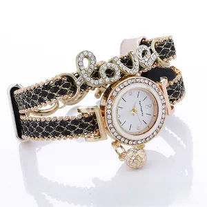 Detailed view of gold rhinestone Love watch with black braided leather strap