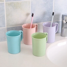 Quatre gobelets à dents portables en plastique pastel posés sur un lavabo blanc