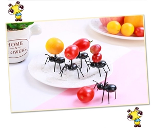 Close-up of black ant-shaped fruit forks carrying fresh grapes and cherry tomatoes
