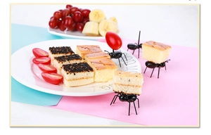 Detailed view of creative ant-shaped plastic fruit picks on dessert and snacks