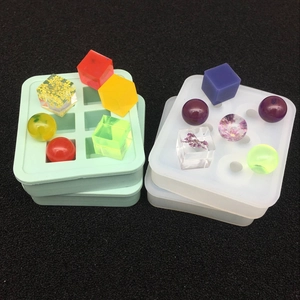 Primer plano de moldes de silicona para joyas de resina con muestras de flores secas y esferas