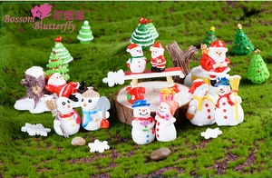 Macro view of miniature resin Santa Claus and snowman figurines on moss background