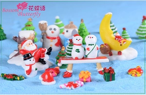 Detailed view of resin Santa Claus and snowman figurines on blue decorative sand