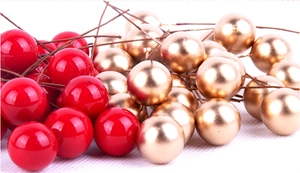 Detail of glossy red and matte gold Christmas berries with wire stems for DIY decor