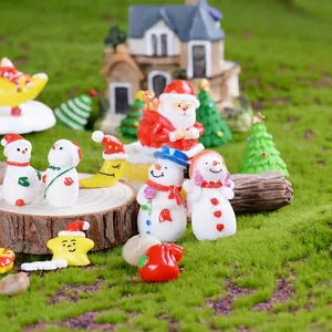 Christmas miniature landscape scene with snowman and Santa figures on mossy wood