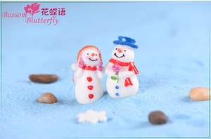 Macro shot of miniature resin snowman pair with floral detail for winter micro landscape