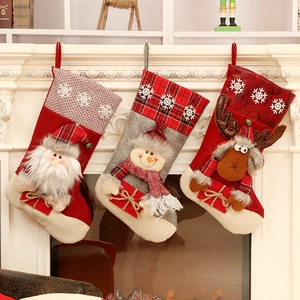 Trois chaussettes de Noël avec Père Noël, bonhomme de neige et renne sur une cheminée