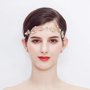 Close-up of bridal floral headband with golden leaves, white daisies and elegant pearls