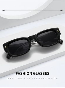 Détail de lunettes de soleil rectangulaires noires avec rivets dorés sur socle blanc
