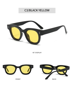 Detail einer ovalen Sonnenbrille mit silbernen Nieten, schwarzem Rahmen und gelben Gläsern