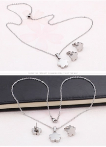 Detailed close-up of polished silver clover pendant necklace and stud earrings set