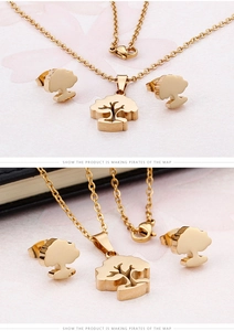 Macro detail of gold-plated tree of life pendant and earrings on textured pink paper