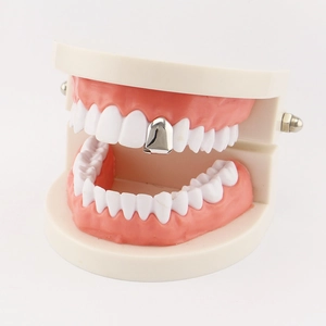 Macro view of a single polished silver grillz tooth cap displayed on a dental model