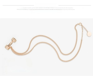 Macro shot of rose gold dumbbell pendant necklace with curb chain and adjustable clasp
