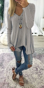 Detail of grey ribbed knit tunic featuring deep V-neck and asymmetrical hemline cut