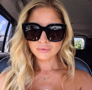 Detail einer schwarzen quadratischen Sonnenbrille mit Metallnieten getragen im Auto