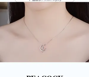 Close-up of a silver cat and moon pendant necklace worn by a model on a box chain