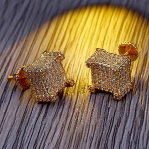 Close-up of gold square stud earrings with full cubic zirconia stones on wooden surface