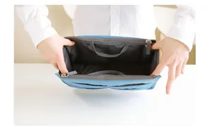 Macro view of light blue multi-pocket handbag organizer with dual handles and zippers