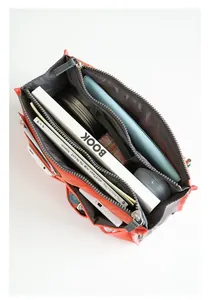 Detail view of orange organizer bag with double zippers and multiple storage pockets