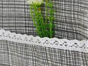 Detail of linen fabric grid pattern with white lace trim and pocket for oven cover