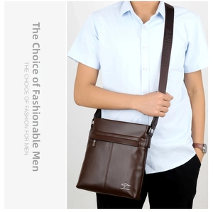 Detail of dark brown leather shoulder bag featuring embossed logo and grain texture